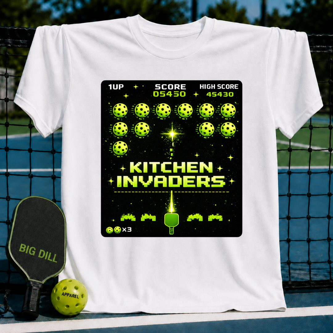 White unisex t-shirt featuring a pixel-art Kitchen Invaders graphic with neon green pickleballs and a paddle design.