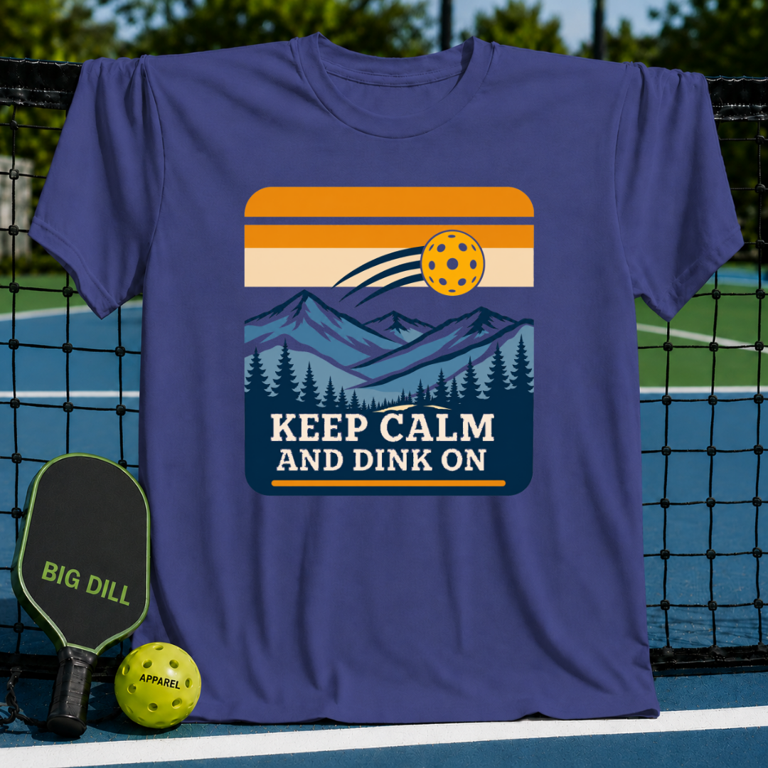 Blue crew neck t-shirt featuring a mountain landscape graphic, pickleball, and the text Keep Calm And Dink On.
