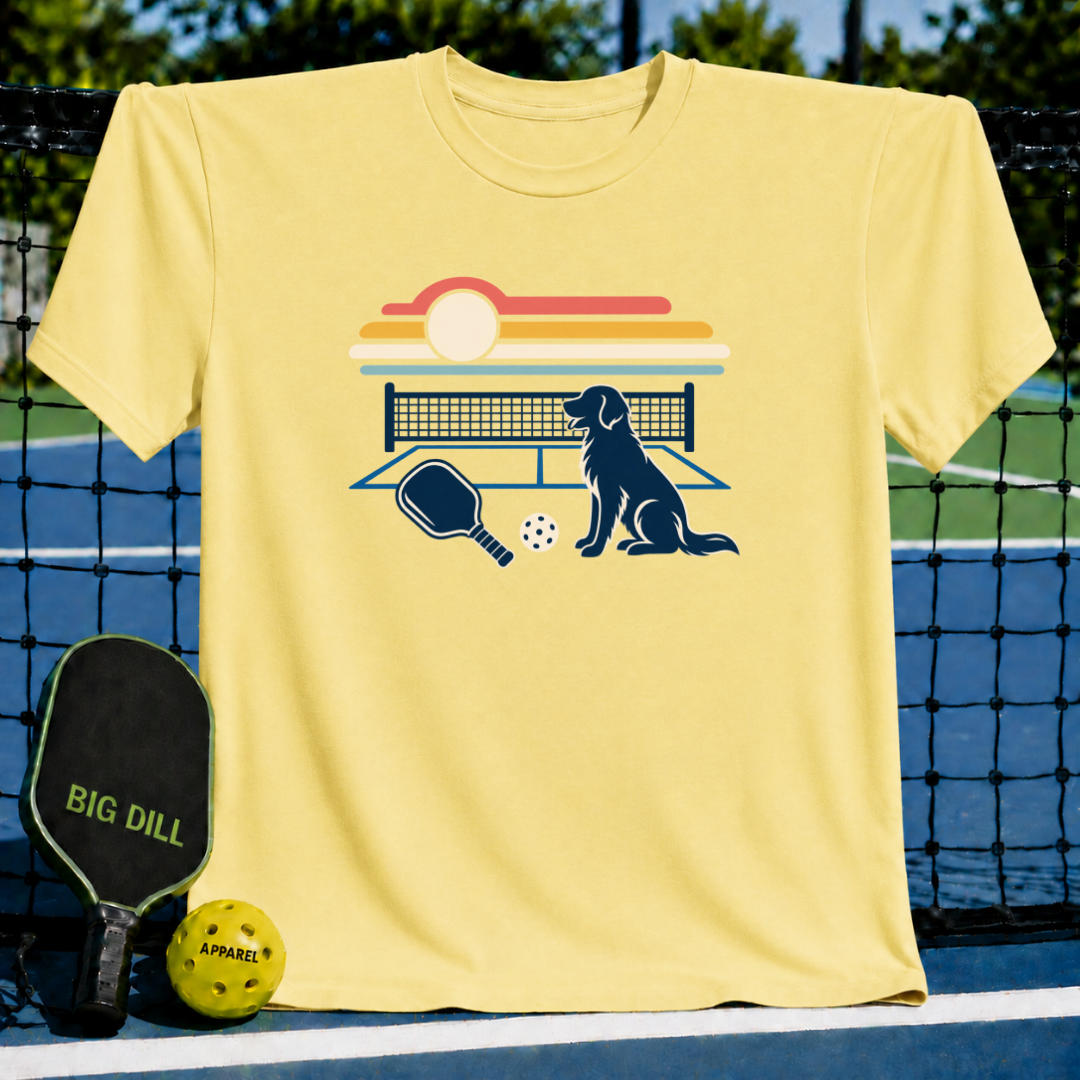 Light yellow crew neck t-shirt featuring a retro sunset, pickleball court, paddle, and dog graphic print.