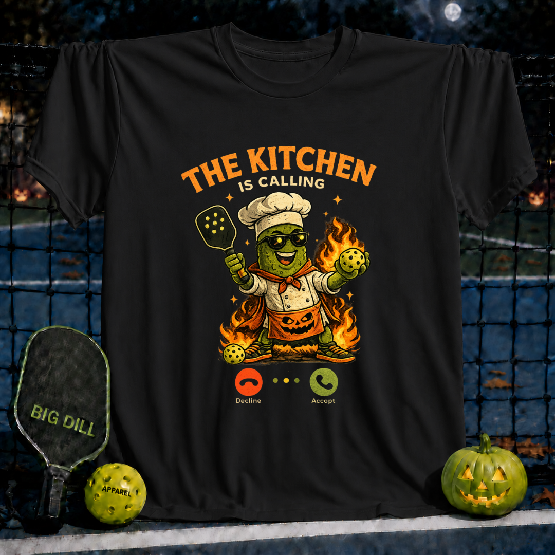 Black unisex t-shirt featuring a chef pickleball character, Halloween flames, and The Kitchen Is Calling graphic.