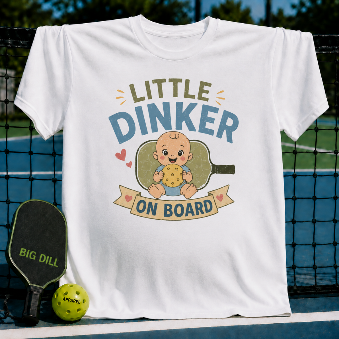 White maternity t-shirt with Little Dinker On Board graphic featuring a baby holding a pickleball on a court background.
