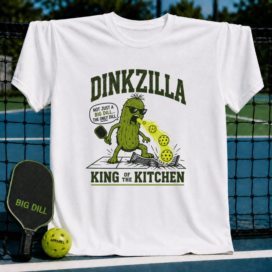White unisex t-shirt featuring a green pickle monster graphic with a pickleball paddle and text, displayed on a court.