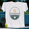 White unisex t-shirt featuring a minimalist sage green and tan pickleball court graphic with a net and ball.