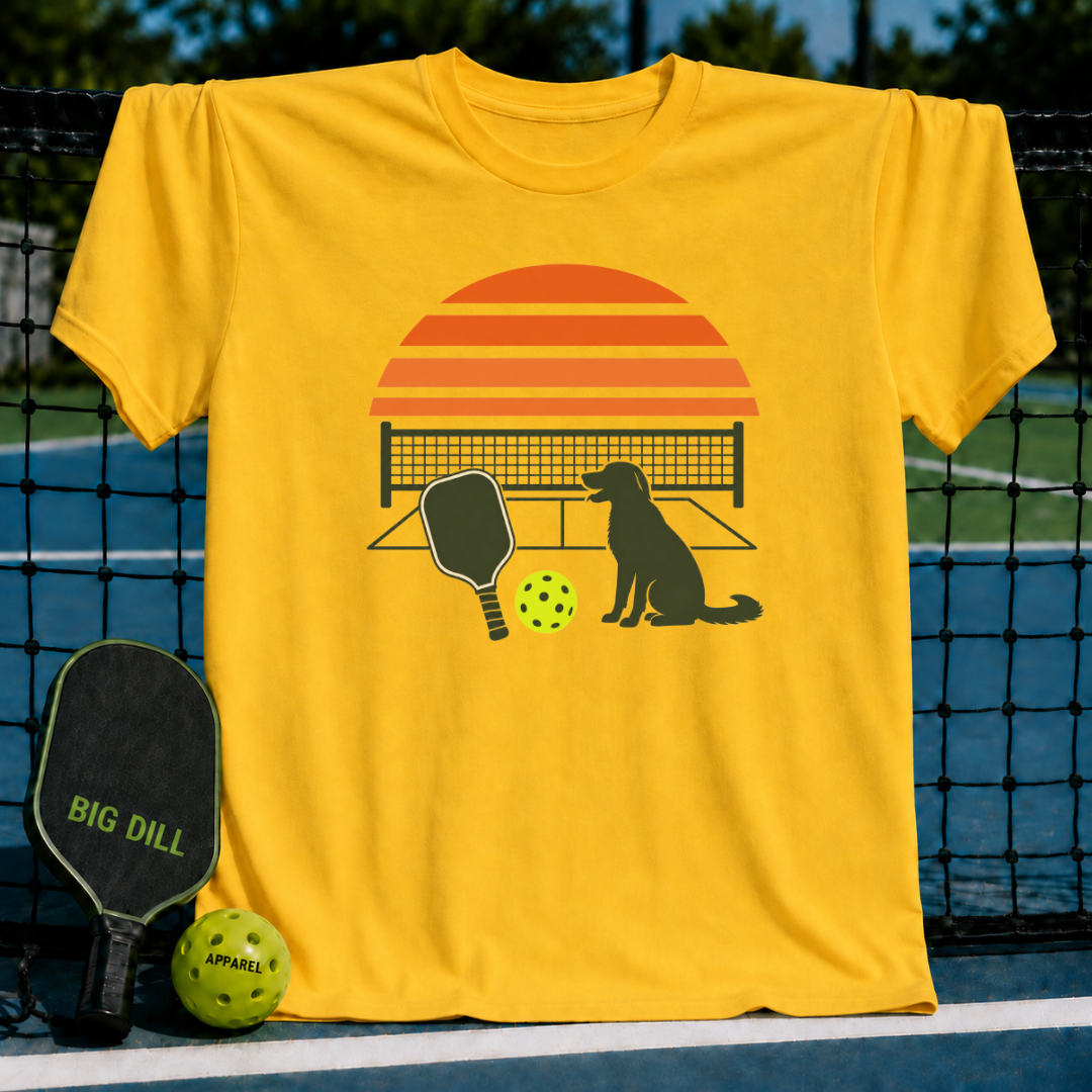 Bright yellow crew neck t-shirt featuring a retro sunset, pickleball paddle, ball, and dog graphic on a court background.