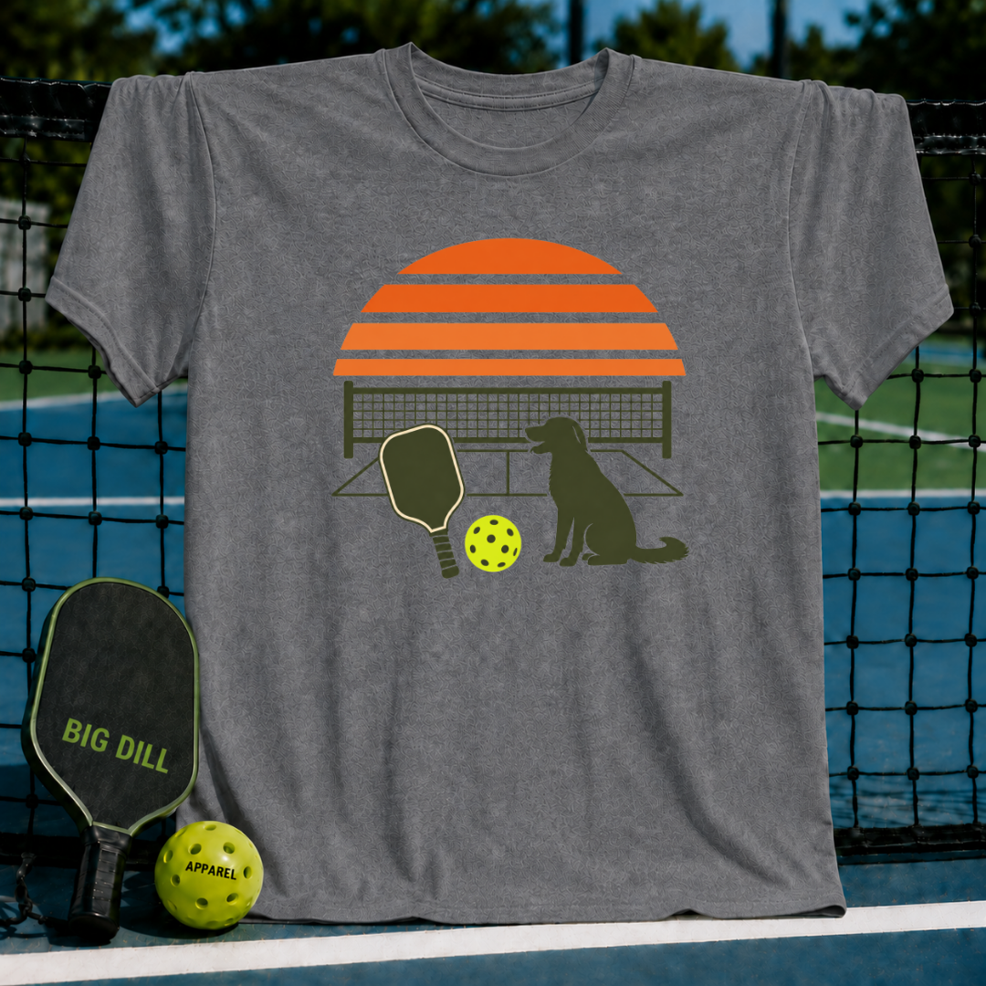 Grey t-shirt featuring a retro orange sunset, pickleball paddle, ball, and dog silhouette graphic.