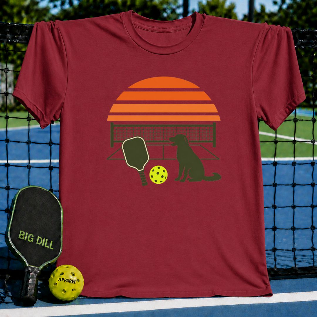 Maroon crew neck t-shirt featuring a retro sunset, pickleball paddle, ball, and dog graphic on a pickleball court background.