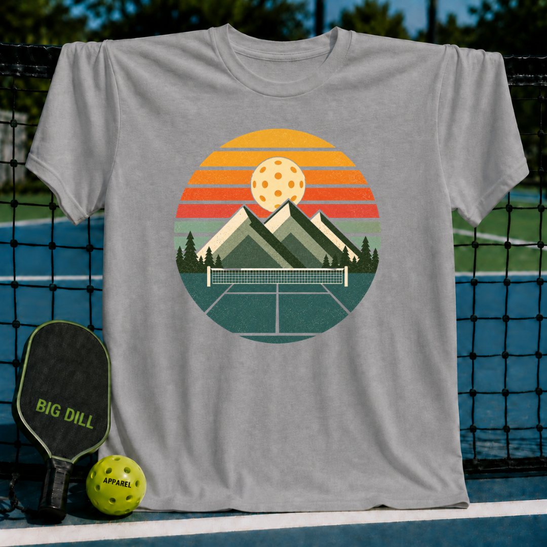 Grey unisex t-shirt featuring a retro circular graphic of mountains, a pickleball net, and a sunset over a court.