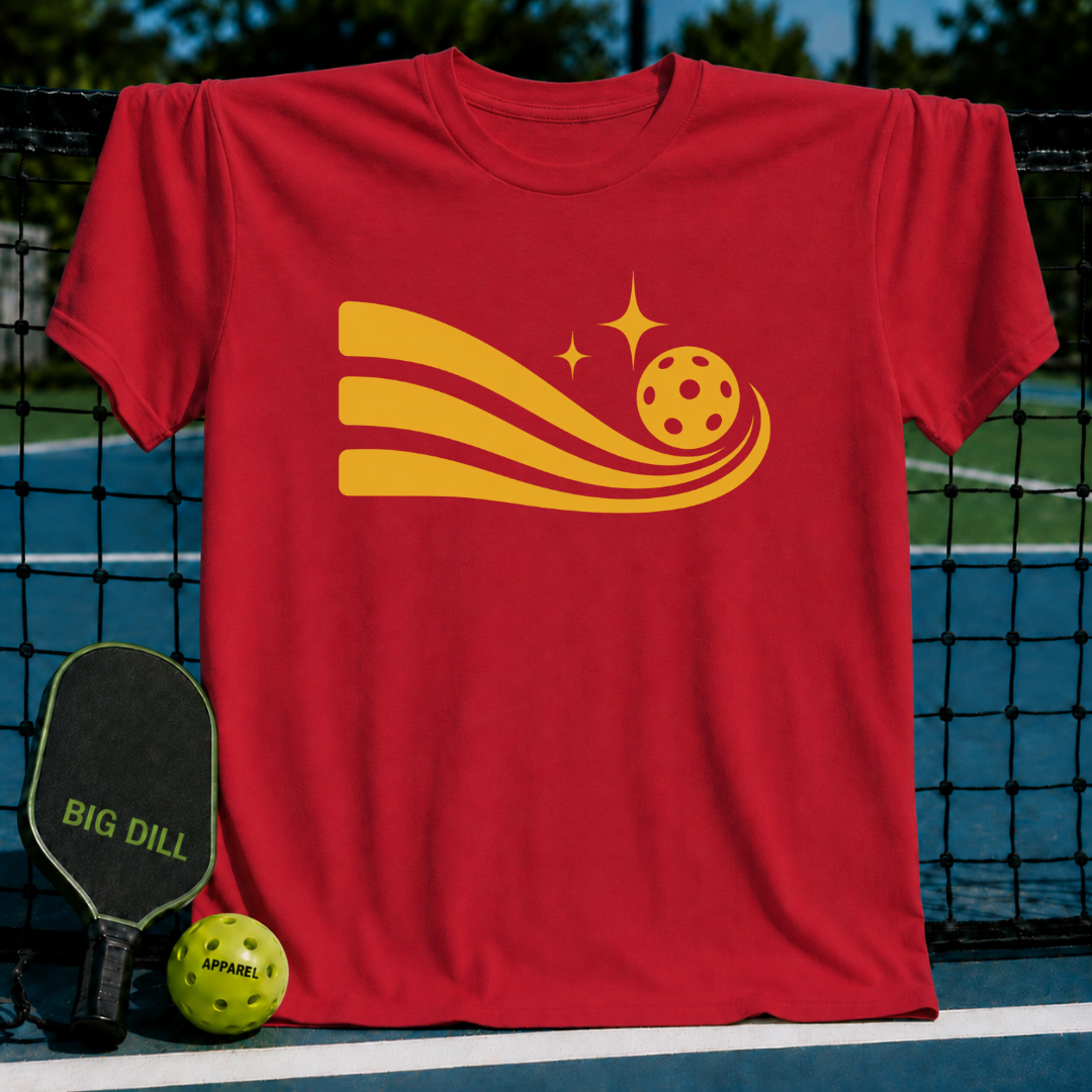 Red unisex Solar Flow 2 t-shirt featuring a golden pickleball graphic with motion trails, displayed on a pickleball court net.