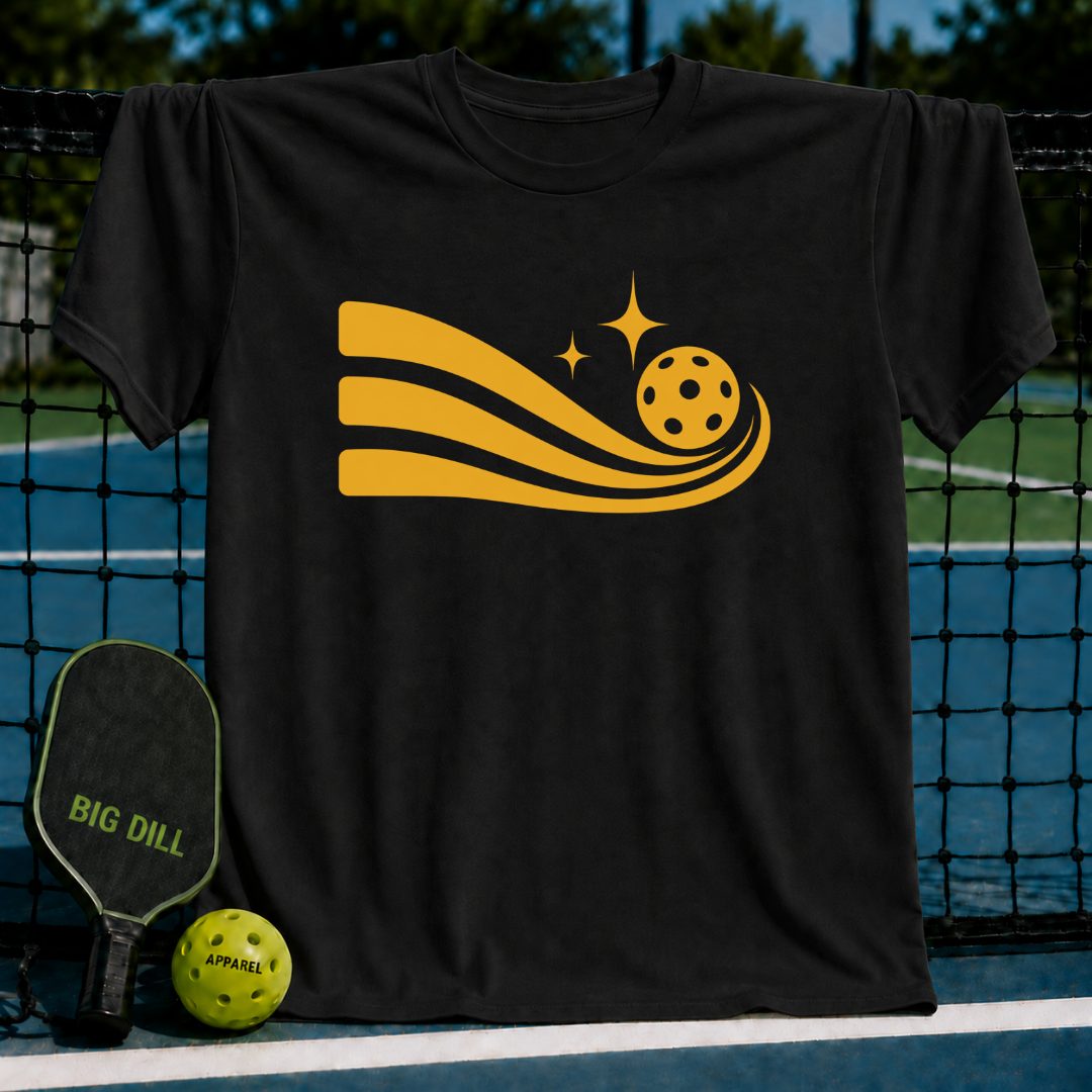 Black unisex t-shirt featuring a gold pickleball graphic with motion trails, displayed on a pickleball court net.
