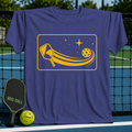 Soft purple unisex t-shirt featuring a yellow graphic of a pickleball paddle and ball with a cosmic starlit trail.