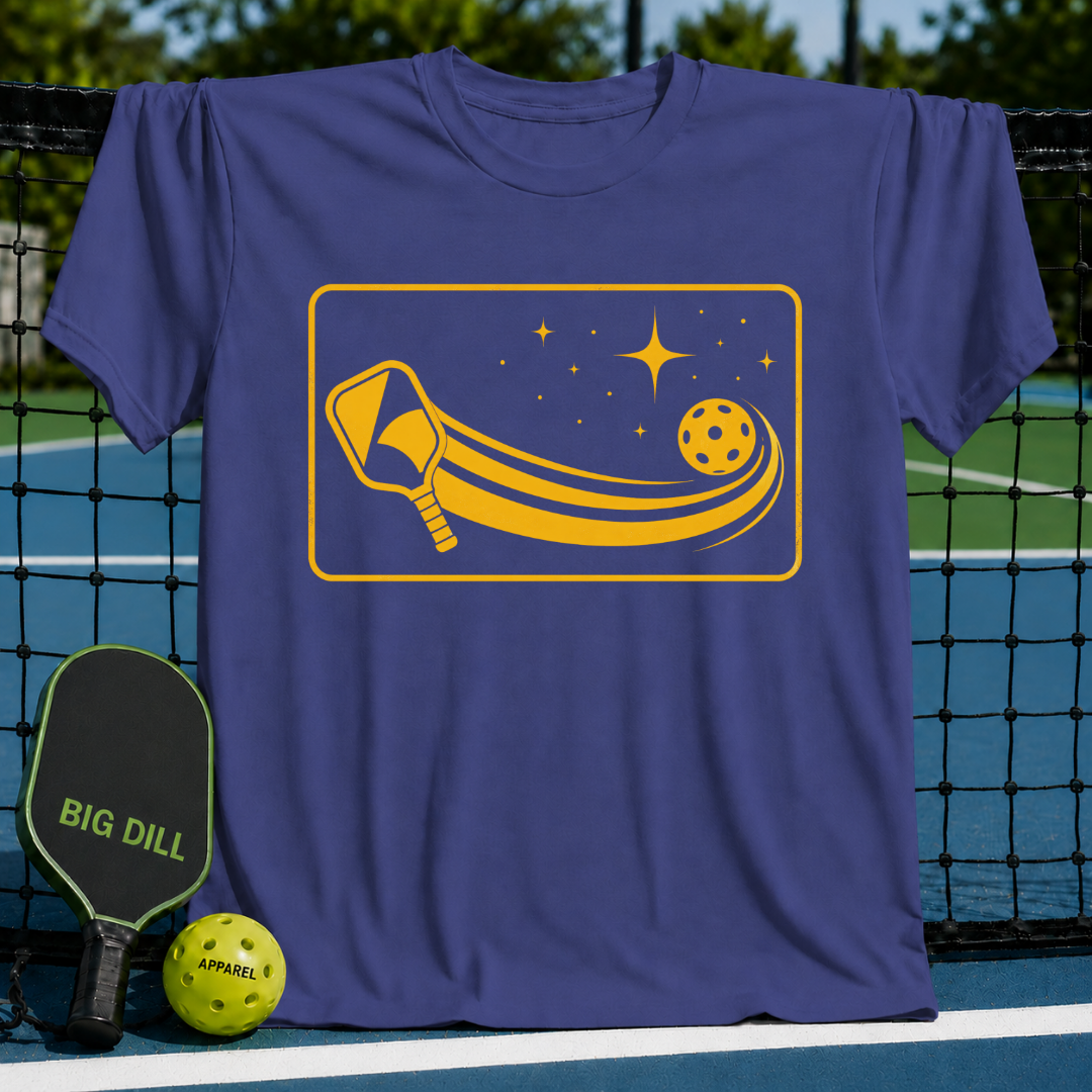 Soft purple unisex t-shirt featuring a yellow graphic of a pickleball paddle and ball with a cosmic starlit trail.