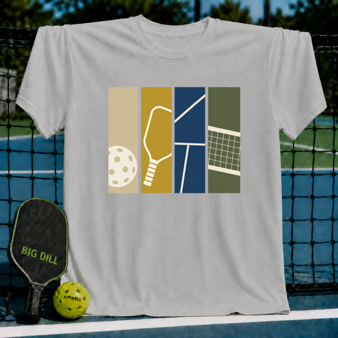 Light gray Swatches T-shirt featuring a colorful graphic of pickleball equipment and court elements on a pickleball court.