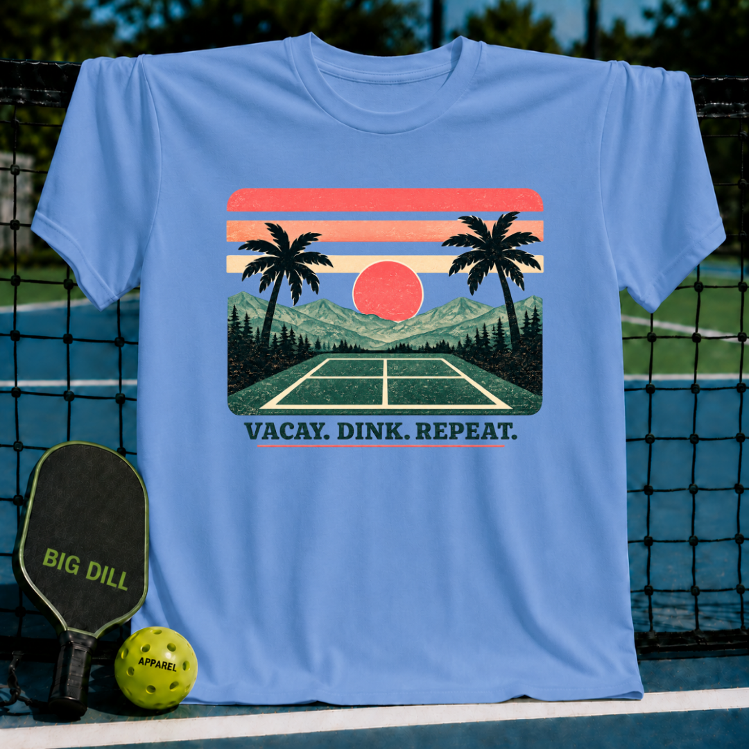 Light blue crewneck t-shirt featuring a retro sunset, palm tree, and pickleball court graphic with Vacay. Dink. Repeat. text.