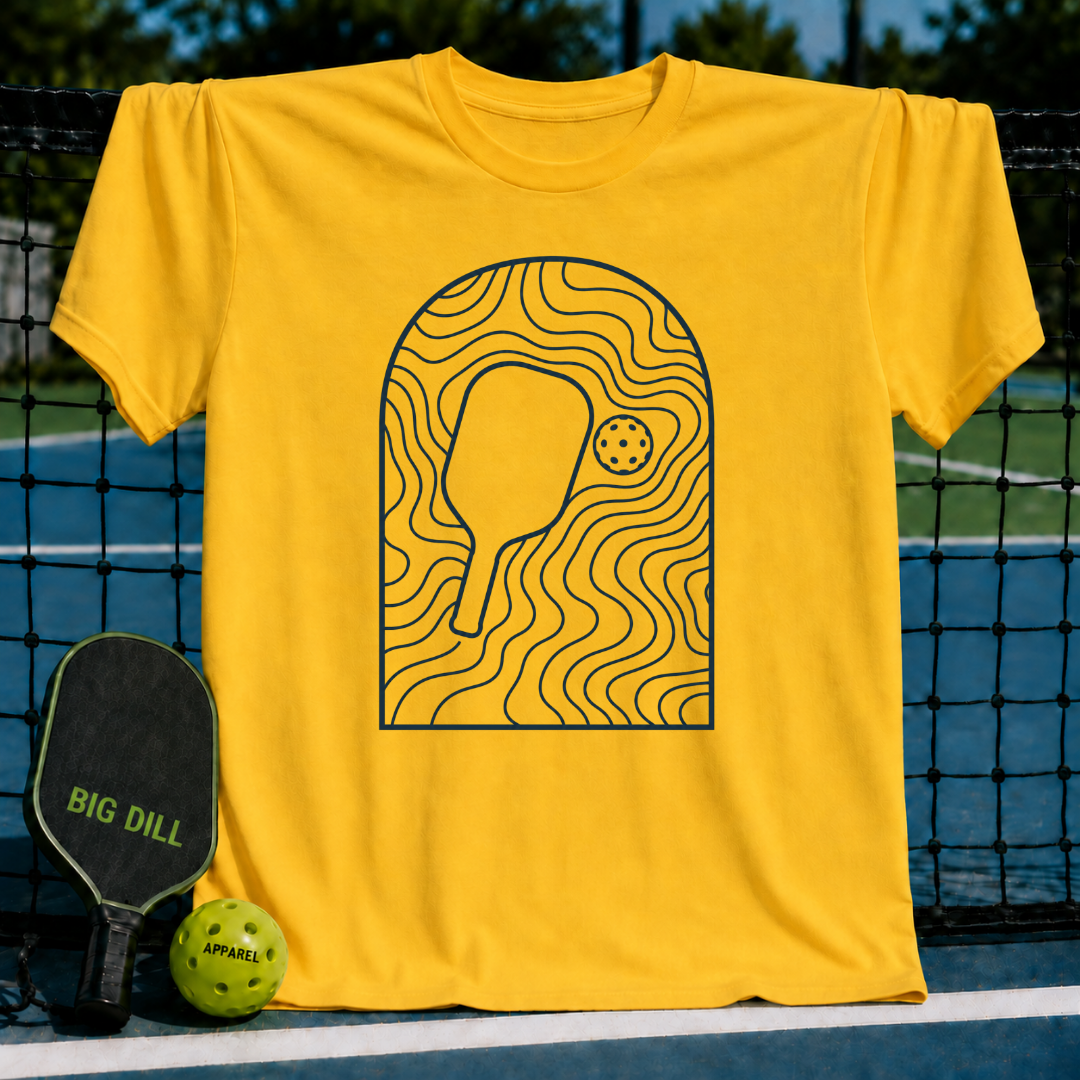 Bright yellow unisex t-shirt featuring a minimalist dark blue arched line art graphic of a pickleball paddle and ball.