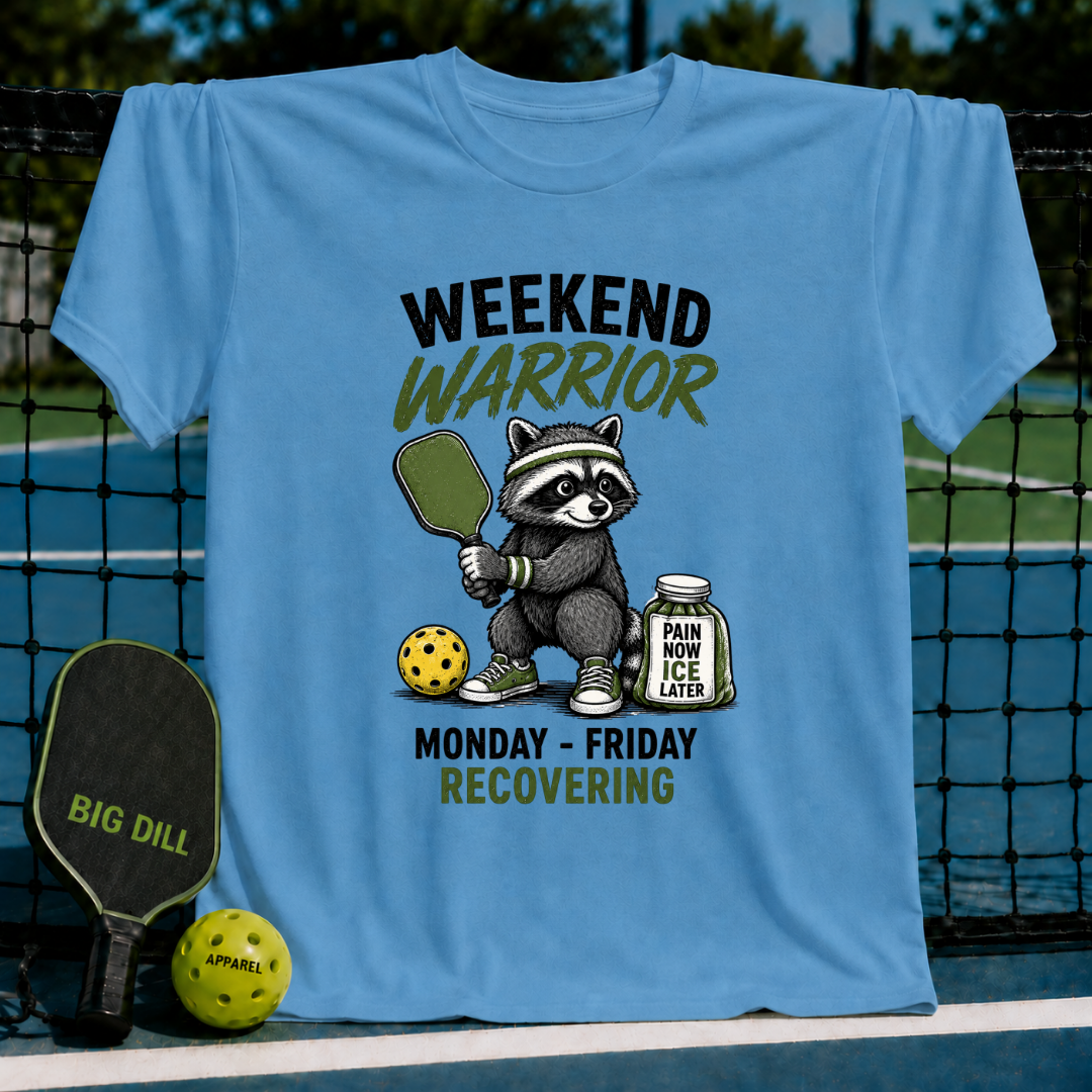 Ocean blue unisex t-shirt featuring a raccoon pickleball player graphic with text reading Weekend Warrior and Recovering.