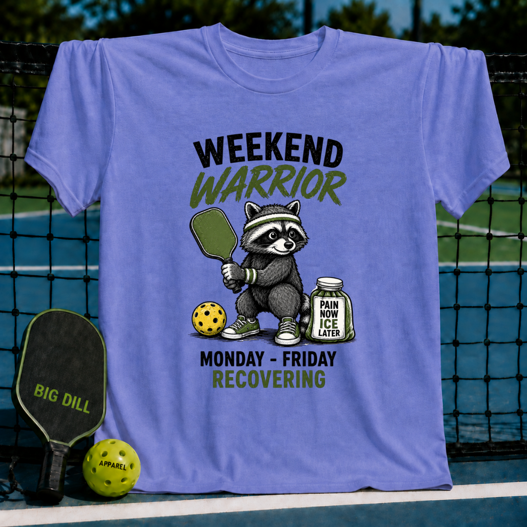 Bright blue unisex t-shirt featuring a raccoon pickleball player with a paddle, ball, and ice jar graphic.