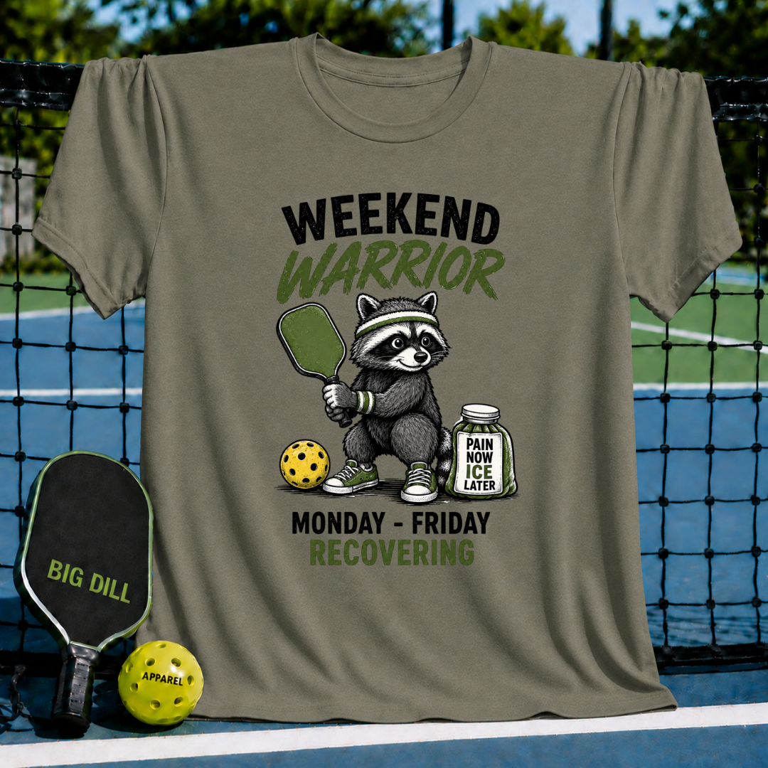 Olive green unisex t-shirt featuring a raccoon pickleball player illustration with the text Weekend Warrior and Pain Now, Ice Later.